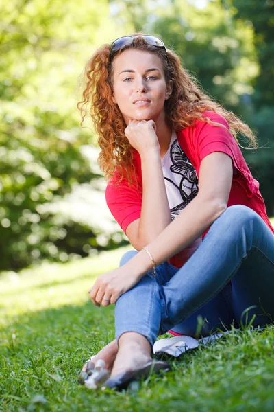 Mulher sentada na grama no parque — Fotografia de Stock