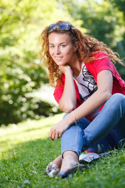 Vrouw zitten op gras in park — Stockfoto
