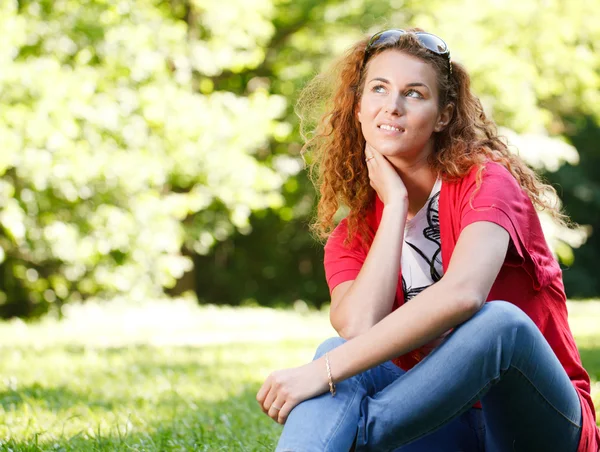 Женщина сидит на траве в парке — стоковое фото