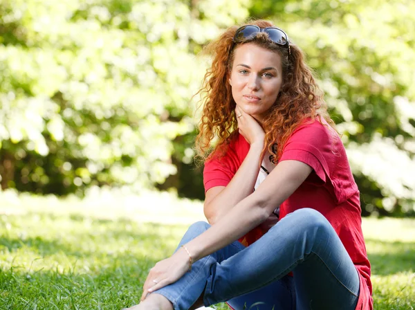 Kvinna sitter på gräset i parken — Stockfoto