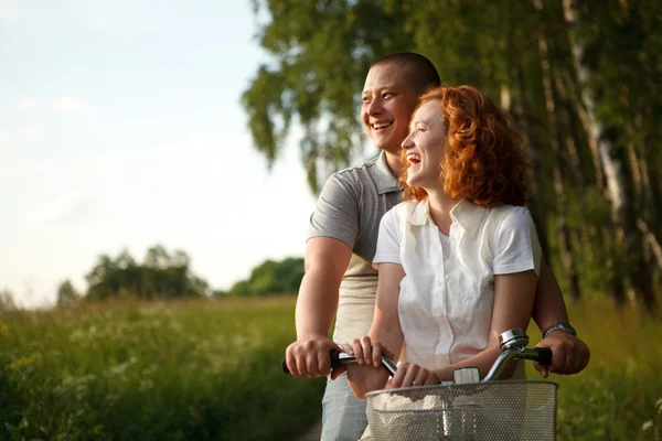 Jovem casal sentado uma bicicleta e olhando para algo — Fotografia de Stock