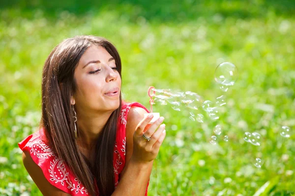 Beautiful woman blowing soap bubbles — Stock Photo, Image