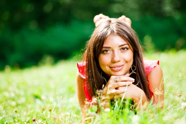 Schöne Frau auf einem Gras liegend — Stockfoto