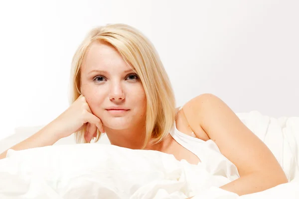 Güzel bir gülümseyen genç kadın yatakta yatan — Stok fotoğraf