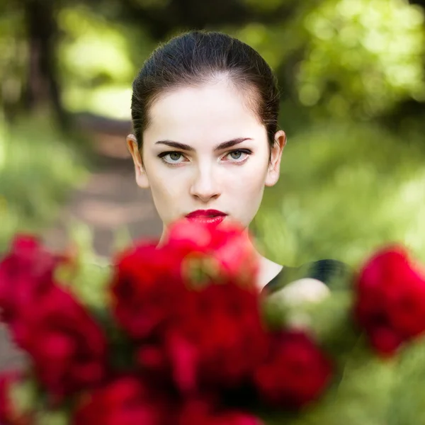 Frau mit roten Lippen schenkt Blumen. Stockbild