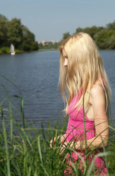 Smutný blondýnka čeká na břehu řeky. — Stock fotografie