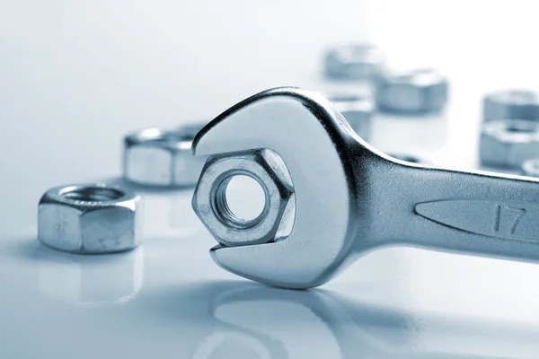 Tuercas metálicas y llave — Foto de Stock