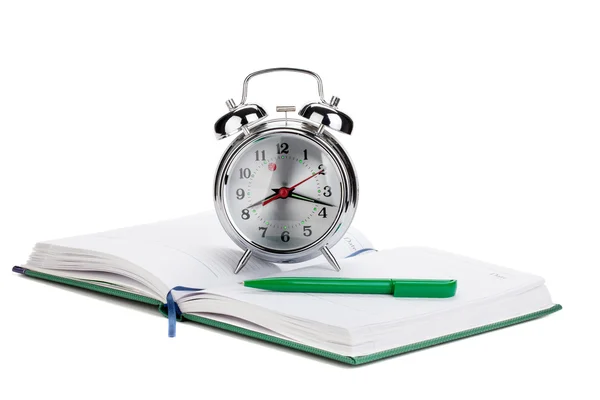 Alarm clock and pen on notepad — Stock Photo, Image