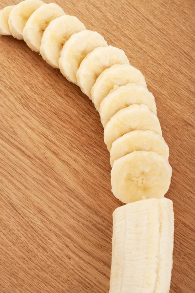 Aufgeschnittene Bananen auf einem hölzernen Hintergrund — Stockfoto