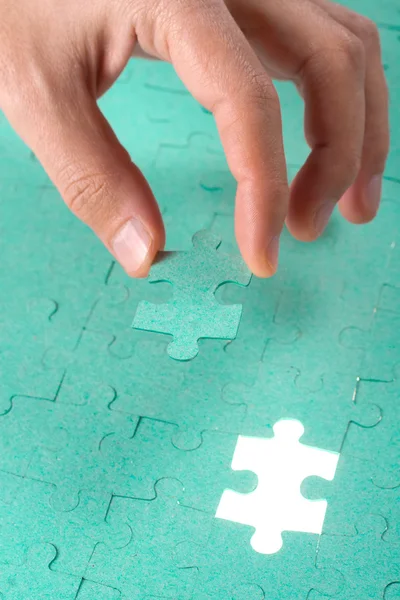 Рука вставляє відсутній шматок зеленої головоломки в дірку — стокове фото
