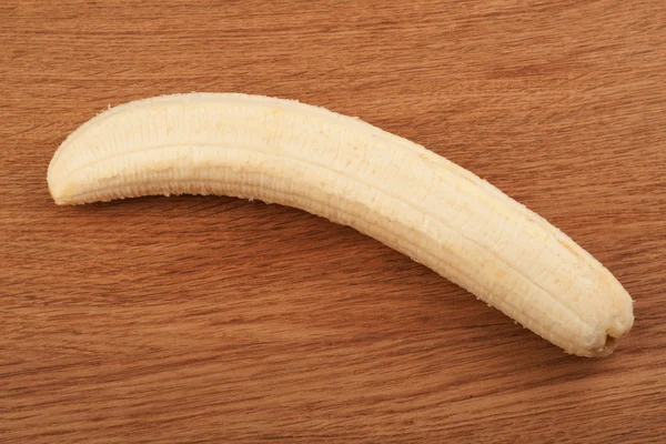 Banana madura descascada em um fundo de madeira — Fotografia de Stock