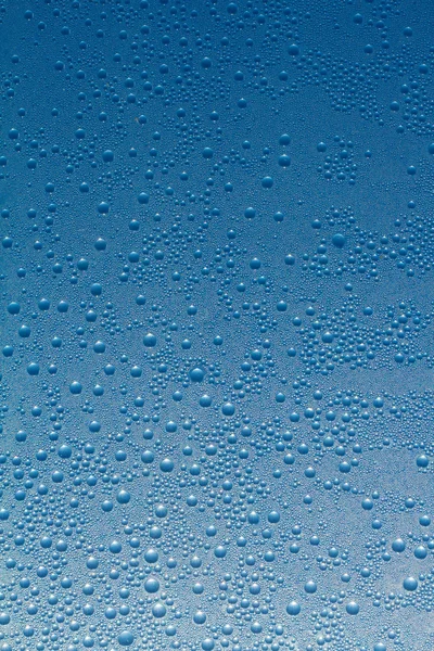 Gotas de água em um fundo de vidro azul — Fotografia de Stock