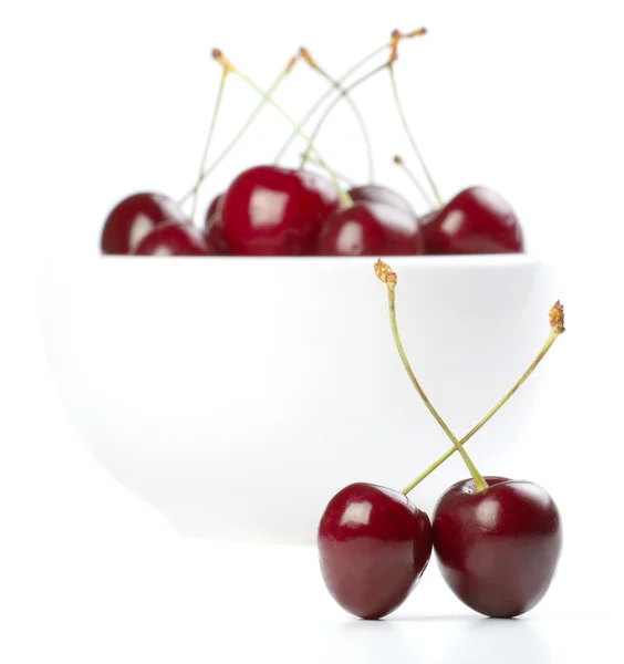 Rote reife Kirschen und ein Teller auf weißem Hintergrund — Stockfoto
