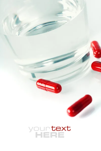 Красные таблетки и вода — стоковое фото