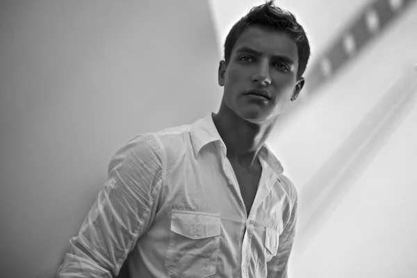 Молодой стильный мужчина в белой рубашке на белой стене перерыва — стоковое фото