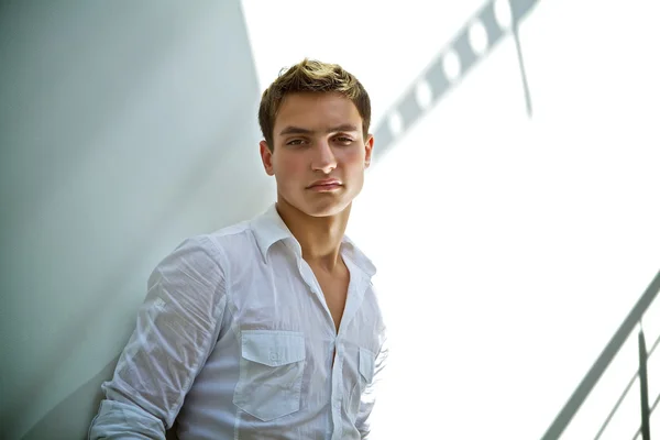 Stilvoller junger Mann im weißen Hemd an einer weißen Pausenwand — Stockfoto