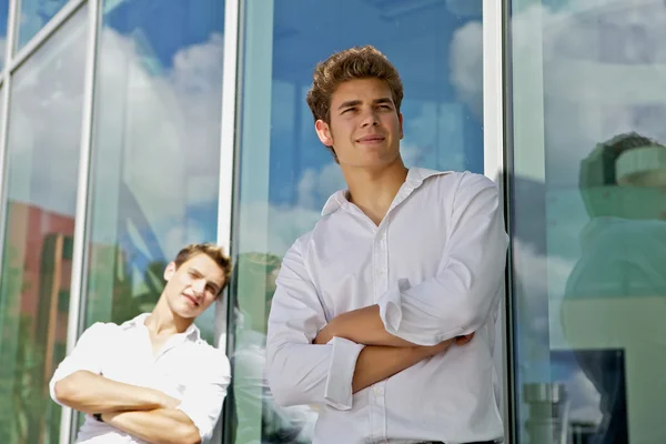 Dois homens atraentes ficam perto do edifício de negócios moderno — Fotografia de Stock