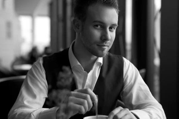 Der junge attraktive Geschäftsmann macht eine Kaffeepause. Schwarz-Weiß-Foto. — Stockfoto