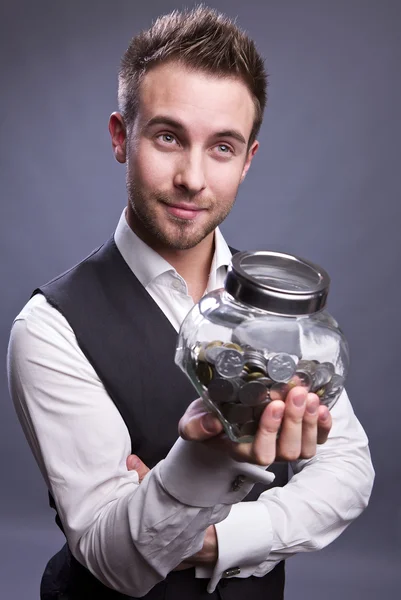 Young business man holding jar with coins — Stock Photo, Image