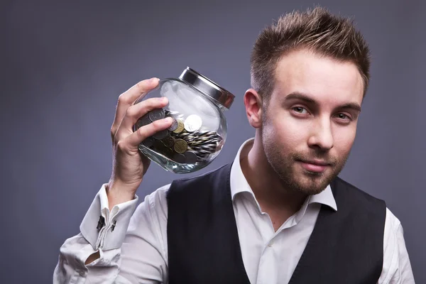Junger Geschäftsmann hält Glas mit Münzen — Stockfoto