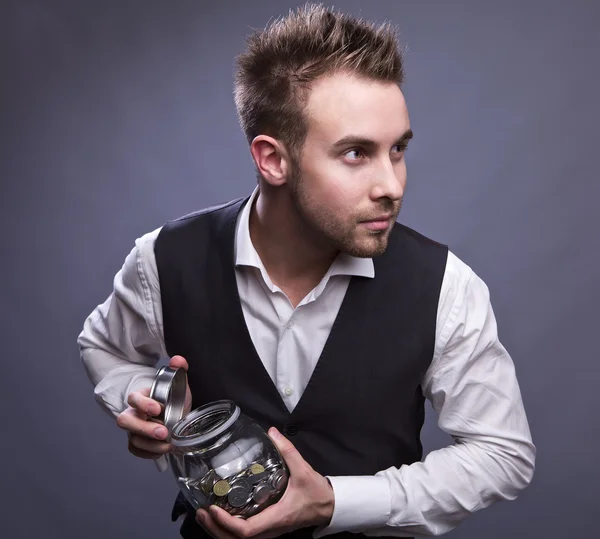 Young business man holding jar with coins — Stock Photo, Image