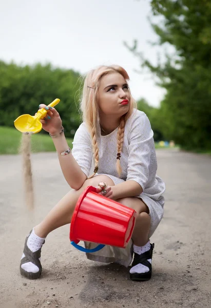Beautiful young fashion girl sits on park road. — Stock Photo, Image