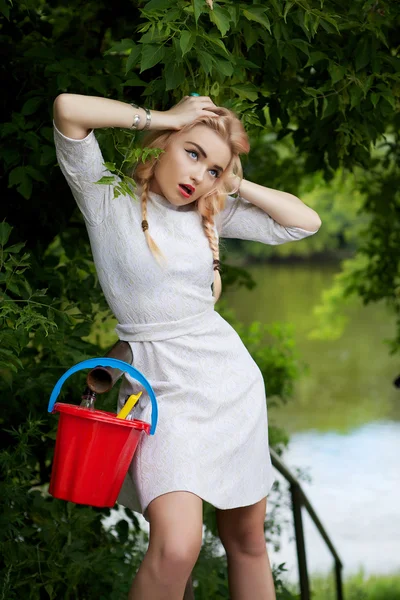 La joven rubia de moda posa en la avenida Park con un cubo rojo . —  Fotos de Stock