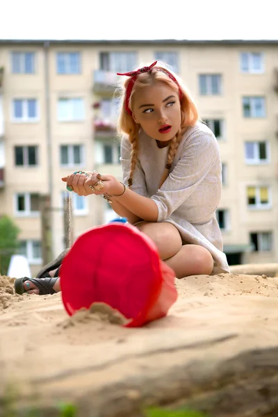 Fashion blond girl In a sandbox. Photo. — Stock Photo, Image