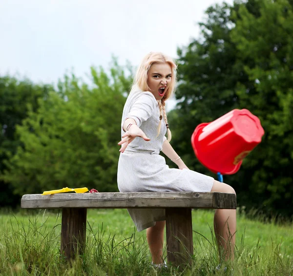 Emocionální blondýnka dělá kapku červeného kbelík. Foto s pohybem. — Stock fotografie