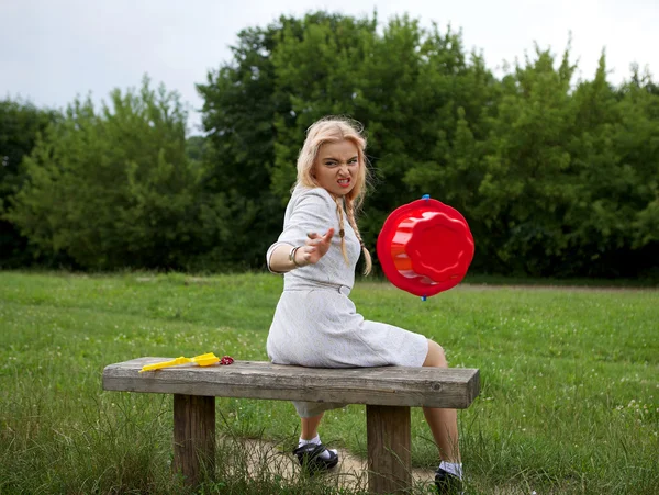 Emotional blonde does the drop by red bucket. Photo with motion. — Stock Photo, Image