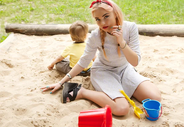 Mode blond meisje in een zandbak. — Stockfoto