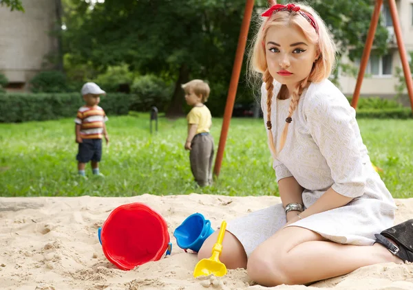 Mode blond meisje in een zandbak. — Stockfoto