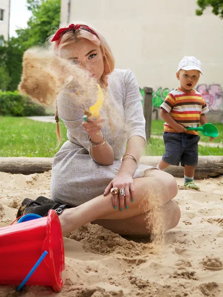 Piękna, młoda dziewczyna siedzi w piaskownicy dla dzieci. — Zdjęcie stockowe