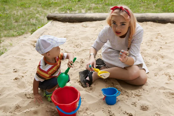 Szép fiatal lány ül a gyermekeknek homokozó. — Stock Fotó