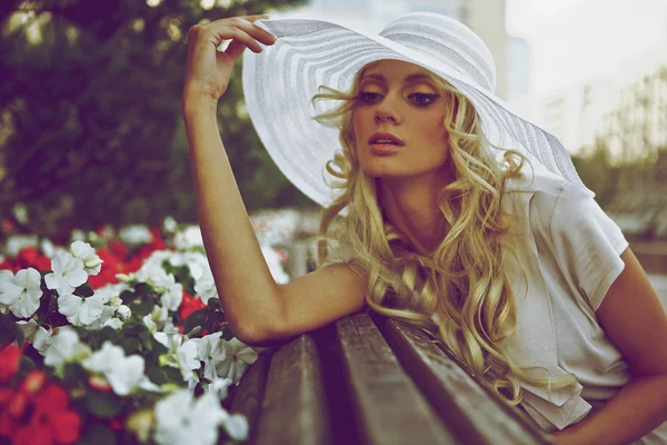 Portrét krásné blond ženy v bílé retro klobouk umístění poblíž parku — Stockfoto