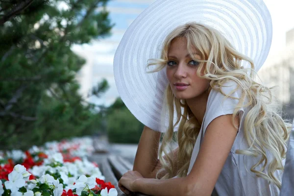 Retrato de mulher loira bonita em chapéu retro branco situado perto do parque — Fotografia de Stock