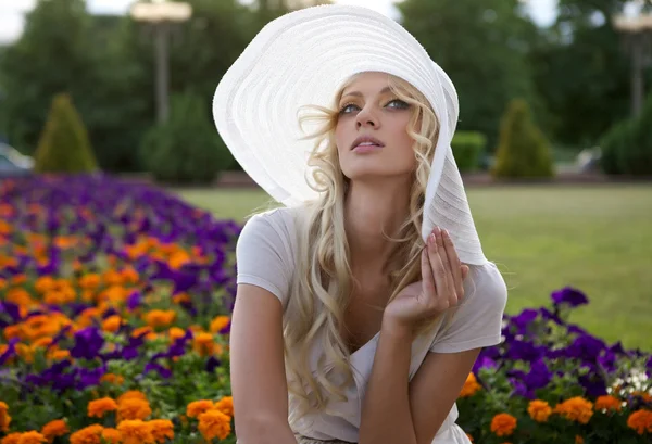 Portrait of beautiful blond woman in white retro hat siting near park — Stock Photo, Image