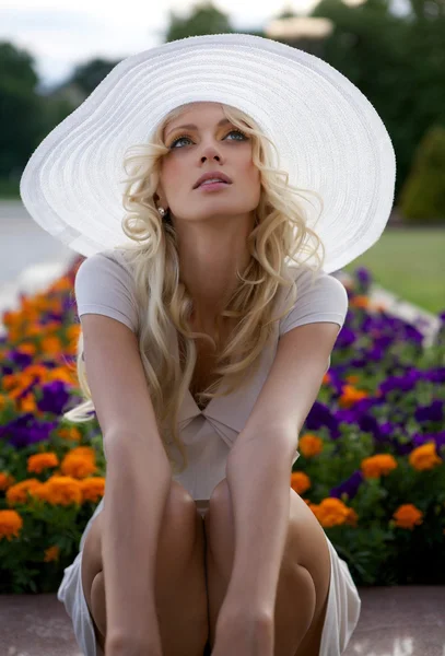 Portret van mooie blonde vrouw in witte retro hoed aanbrengen in de buurt van park — Stockfoto