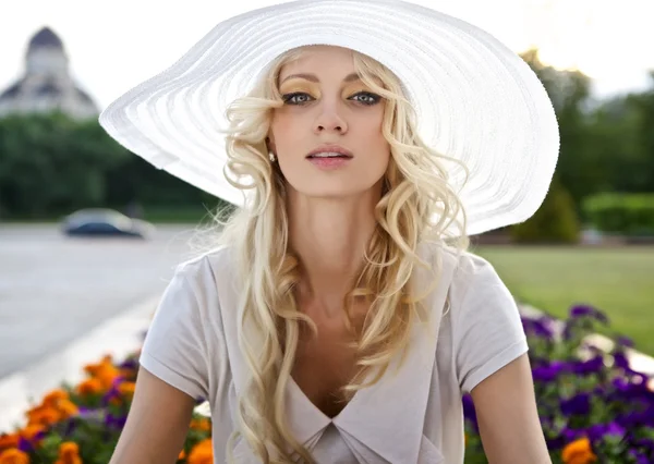 Portret van mooie blonde vrouw in witte retro hoed aanbrengen in de buurt van park — Stockfoto