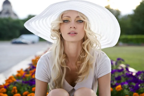 Портрет красивой блондинки в белой шляпе ретро, сидящей рядом с парком — стоковое фото