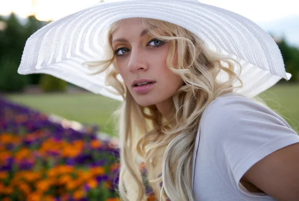 Portrét krásné blond ženy v bílé retro klobouk umístění poblíž parku — Stock fotografie