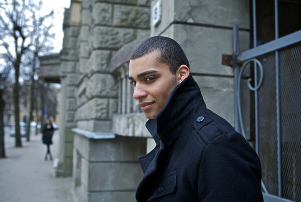 Young beautiful mulatto near old wold. Man and urban. Evening outdoor shoot