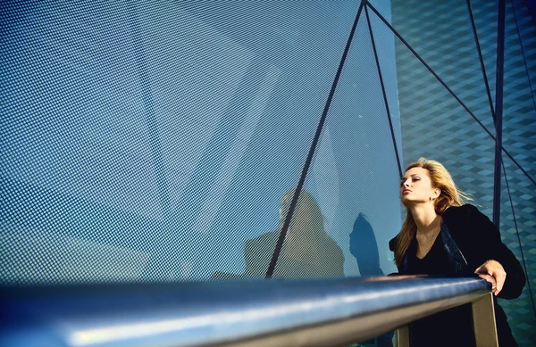 Vacker blondin nära en modern byggnad i glas — Stockfoto