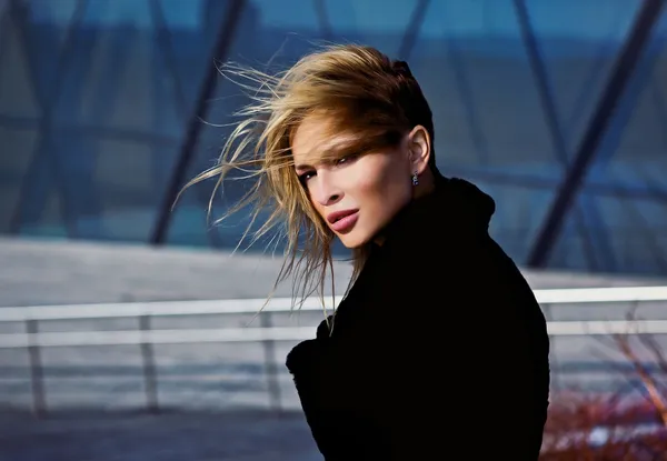 Schöne Blondine in der Nähe eines modernen Gebäudes aus Glas. — Stockfoto