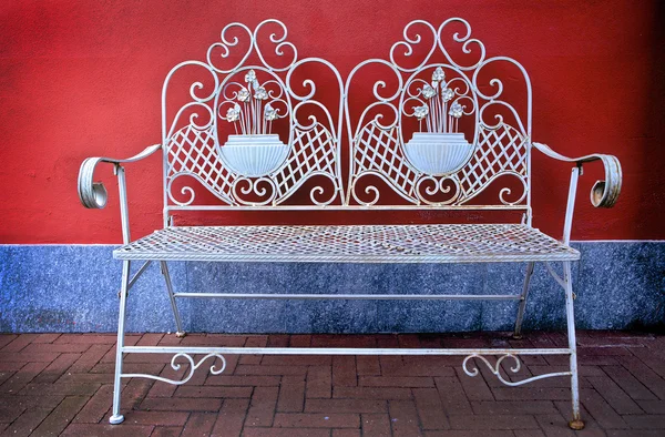 赤い壁の近くの古代の金属のベンチ — ストック写真