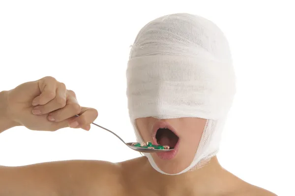 Ung kvinna med bandagerade huvud accepterar medicin — Stockfoto