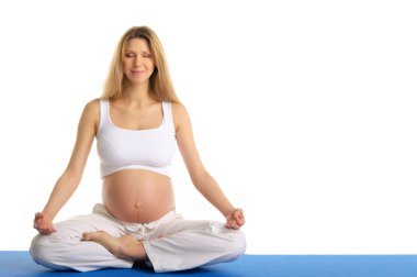 Pregnant woman with ??eyes closed practicing yoga clipart