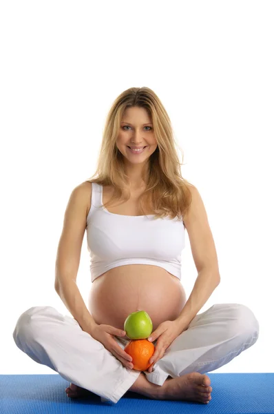 Hamile kadın yoga yapıyor ve meyve saklıyor. — Stok fotoğraf
