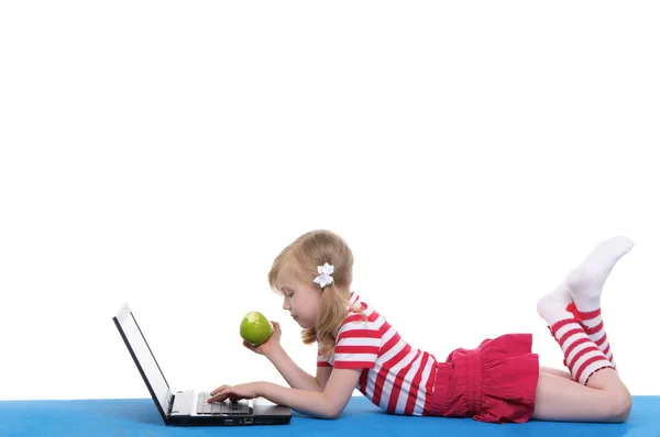 Девушка с яблоком и ноутбуком на ковре — стоковое фото