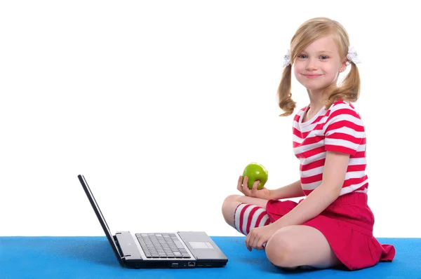 Chica con una manzana y un ordenador portátil sentado en la alfombra —  Fotos de Stock